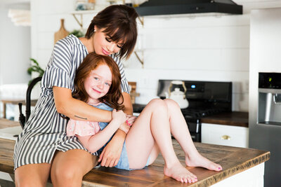 mom and daughter hugging on kitchen counter
