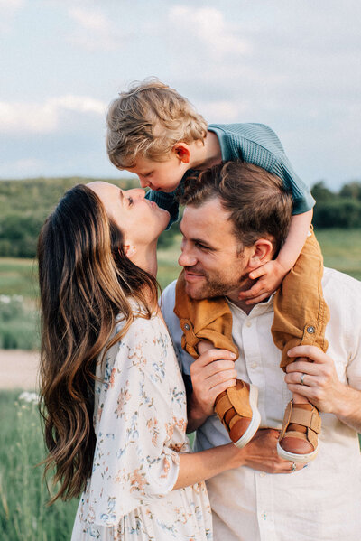 mother kissing boy while on dad's shoulders with Alyssum, Denver family and motherhood photographer