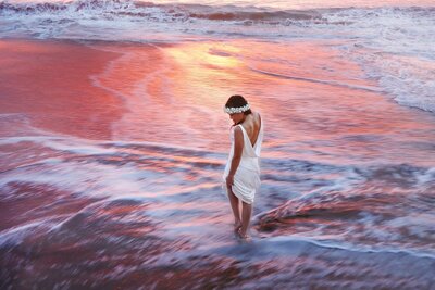 beautiful sunset elopement with bride gazing at sand after her beach elopement in wailea