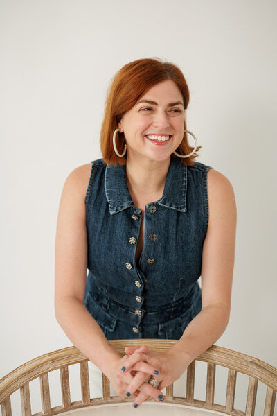 Headshot of Chelsey Heslop in a denim top leaning on the back of a wooden chair