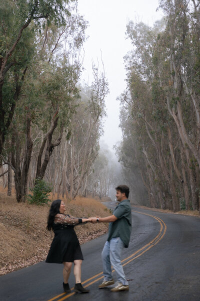 Candid Couples engagement photos at Montana De Oro on the Central Coast, with couple dancing in the road with fog and trees