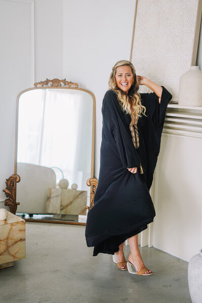 Katie, spiritual entrepreneur coach, smiling in a black outfit, radiating warmth and positivity.