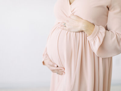 pregnant mother's belly in pink dress during studio session with Madison WI photographer Talia Laird Photography