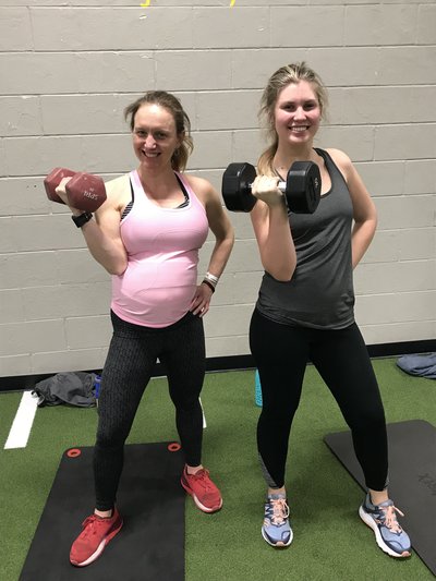 Olympic athlete with her sister holding a dumbbell while working out during pregnancy