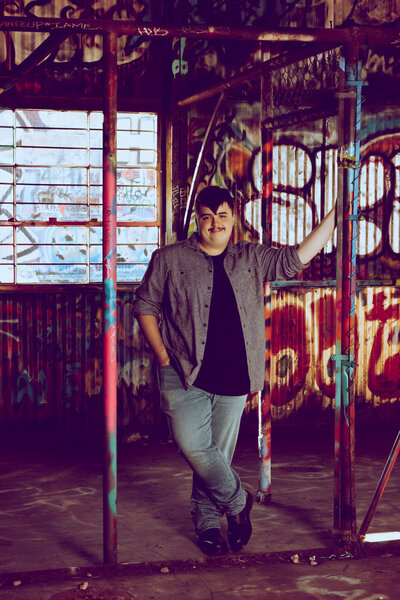 senior-boy-posing-at-fabrication-yard-in-dallas -with-graffiti