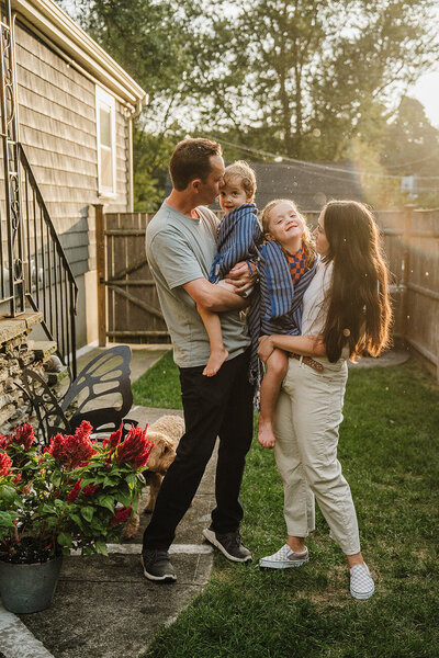 a family snuggles two kids in yard during sunset boston family photos at home