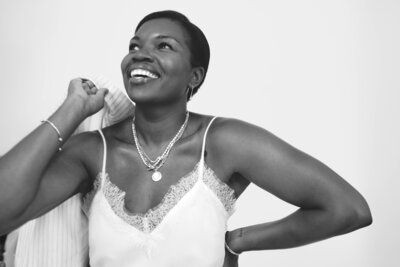 Black career coach for women holding jacket over shoulder in silk top and necklace