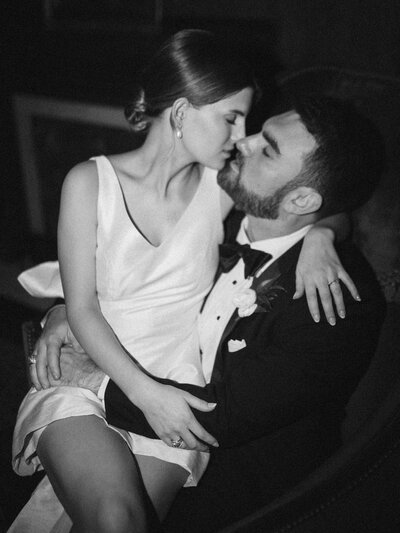 Black and white photo of bride sitting in groom's lap
