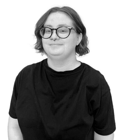 Salon Assistant with a short textured haircut and a bright smile, wearing a black blouse, embodying confidence and professionalism.