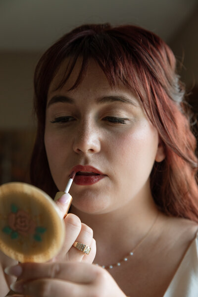 Bride touches up her makeup before her wedding photos at her family home in Portland, Oregon.
