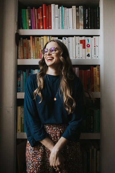 Woman standing in front of a bookshelf looking to the side