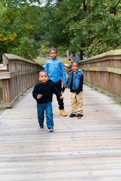 3 small boys posing on wooden bridge for fall family photos