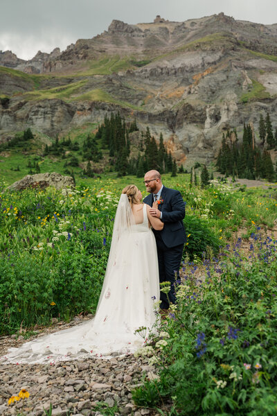 A bride and groom laugh together at sunset on Lake Dillon