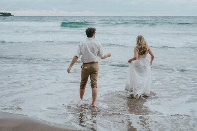 bride and groom on the beach in beach sur, brides dress is getting wet from the waves