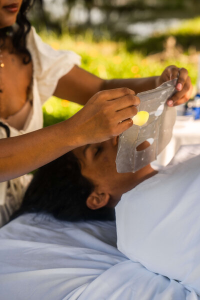 Girl putting a face mask on  her spa client
