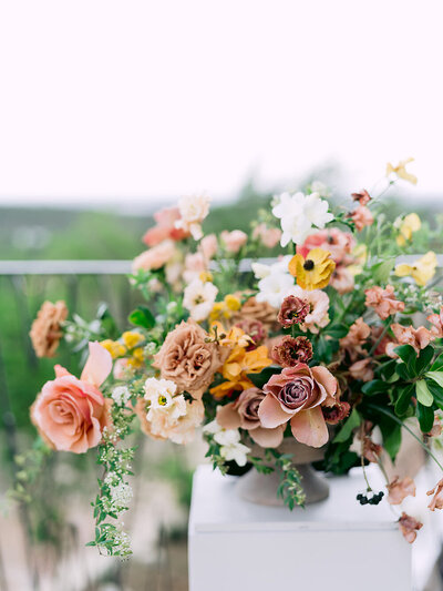 An old-world inspired floral arrangement atop a pedestal as ceremony decor