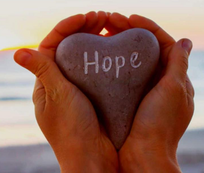 Hands holding a stone engraved with the word Hope, symbolizing healing and encouragement at EnerBea.