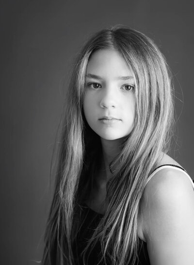 black and white portrait of teen with long blonde hair wearing black tank top
