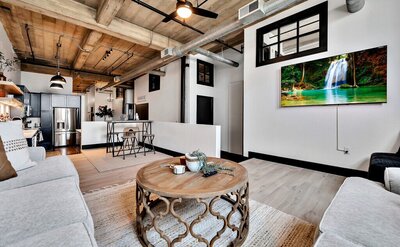 Living room with flat screen TV and streaming services in this three-bedroom, two-bathroom industrial modern loft condo in the historic Behrens building in downtown Waco, TX.