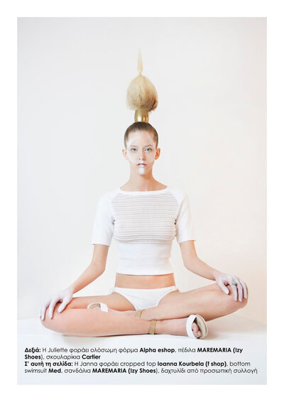 Model wears white shirt and white underwear while sitting cross-legged with white paint on her face.
