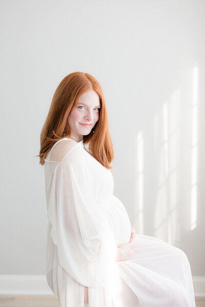Pregnant mom wearing all white in a bright and beautiful louisville newborn photography studio