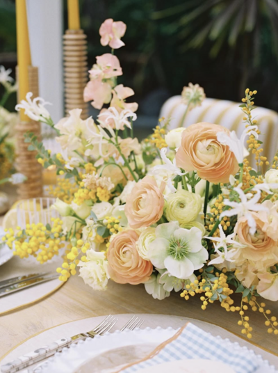 Tropical outdoor cabana wedding in California with yellow striped chairs and pastel florals on the table