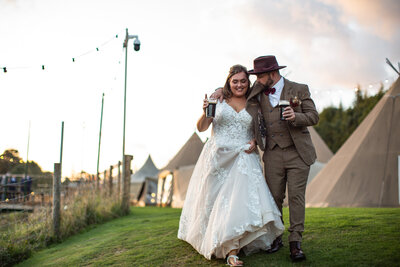 Bride and groom walking in tipi field