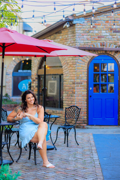 A woman in downtown winter park sitting at a table in a colorful alley