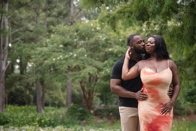 Engaged couple sharing a romantic kiss during a surprise proposal at Glencairn Gardens in Rock Hill, SC, captured by Charlotte proposal photographer DeLong Photography.