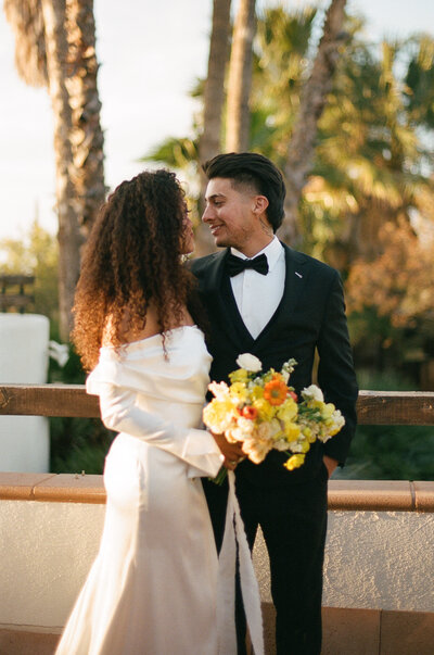 Bride and groom embracing as they lean on vintage getaway car