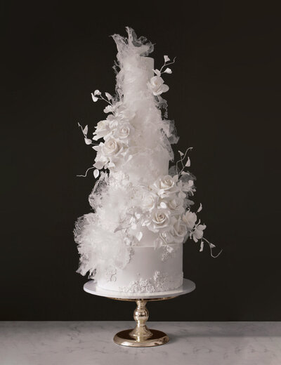 all white wedding cake with delicate floral textures and ethereal translucent waves