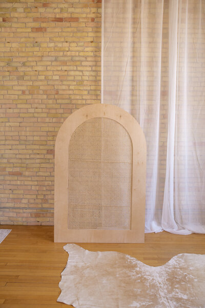 A six foot caned arch set up against a brick wall.