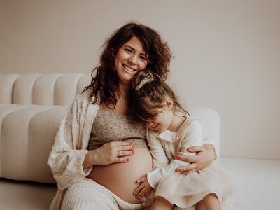 Intimiteit tussen moeder en dochtertje tijdens zwangerschapsshoot in studio