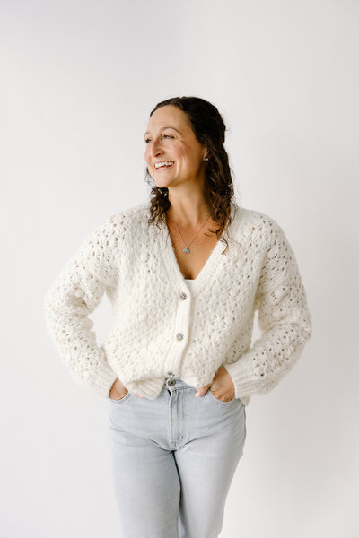 Indianapolis Lifestyle Newborn Photographer Cailtlyn Brady of Capturing Simplicity Photography  smiling over shoulder with hands in pockets