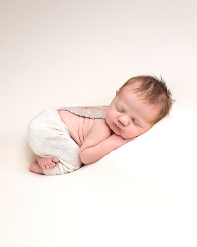 baby boy in overalls  sleeping on white backdrop in portland studio photos