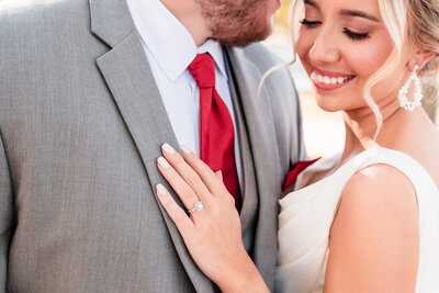 A groom tenderly kisses his bride’s shoulder as she smiles softly, embracing the warmth and intimacy of their wedding day. His hand rests gently over hers, symbolizing love and connection. This heartfelt moment showcases the beauty of Alabama wedding photography.