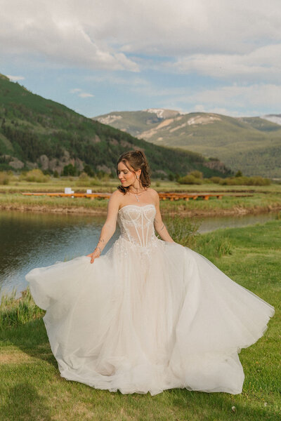 Bride twirling in her wedding dress in an open Colorado mountain meadow — romantic bridal portrait.
