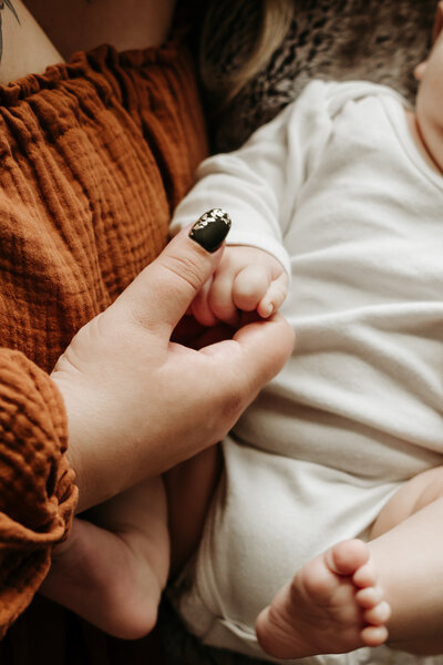 Detailed newborn photo of mom holding baby's hand in lifestyle studio in Annapolis Maryland.
