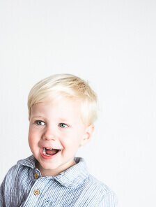 Boy in stripped blue shirt smiling happily at Tampa photographer