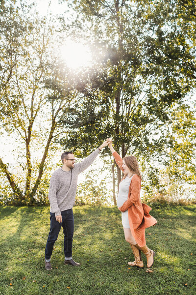 Expecting couple dancing at a park by the lake in Etobicoke