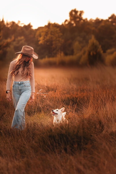 Vrouw en hond samen aan het wandelen tijdens een hondenfotoshoot met MSwitsersphotography. Bewerkt in warme, bruine stijl. 