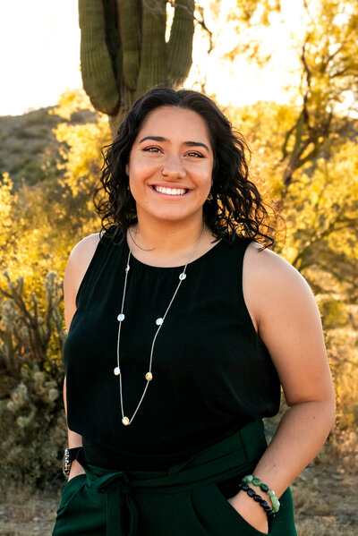 Amber, owner and maternity , newborn and family photographer smiling at camera in a desert location in Phoenix