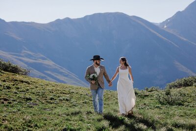 Bride and groom walk hand in hand during Rocky Mountain elopement.