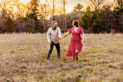 couple running in a field together during their engagement session