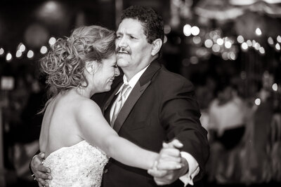 A bride cries while dancing with her father on her wedding day.