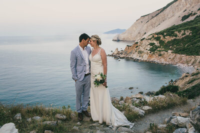 bride and groom standing by ocean