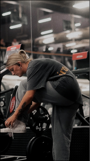 Kaylin in gym bends down to tie her shoe