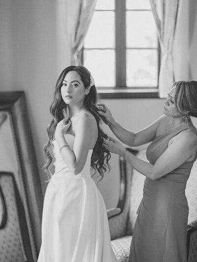 mom helping the bride to put on her dress