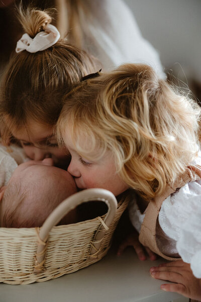 Zusjes zoenen broertje tijdens newborn fotoshoot