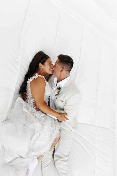 Bride and groom kiss on bouncy house during luxury Minnesota wedding